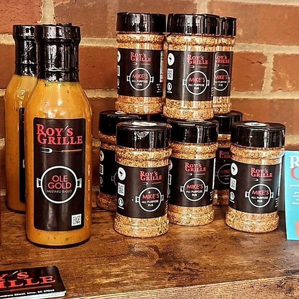 Roy's Grille mustard-based sauces and Mike's All Purpose Rub spices displayed on a wooden shelf.